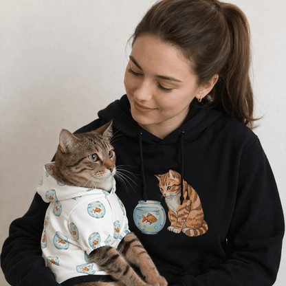 Woman holding a cat wearing a sweater with a black hoodie featuring a cat design.
