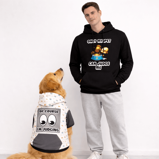 Man wearing a black hoodie with a graphic and text, standing next to a dog wearing a matching hoodie.
