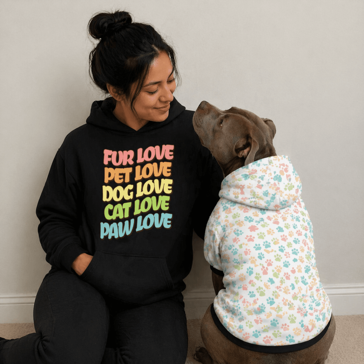 Woman sitting wearing pet love, fur love, cat love, dog love hoodie with her pitbull wearing pastel printed hoodie