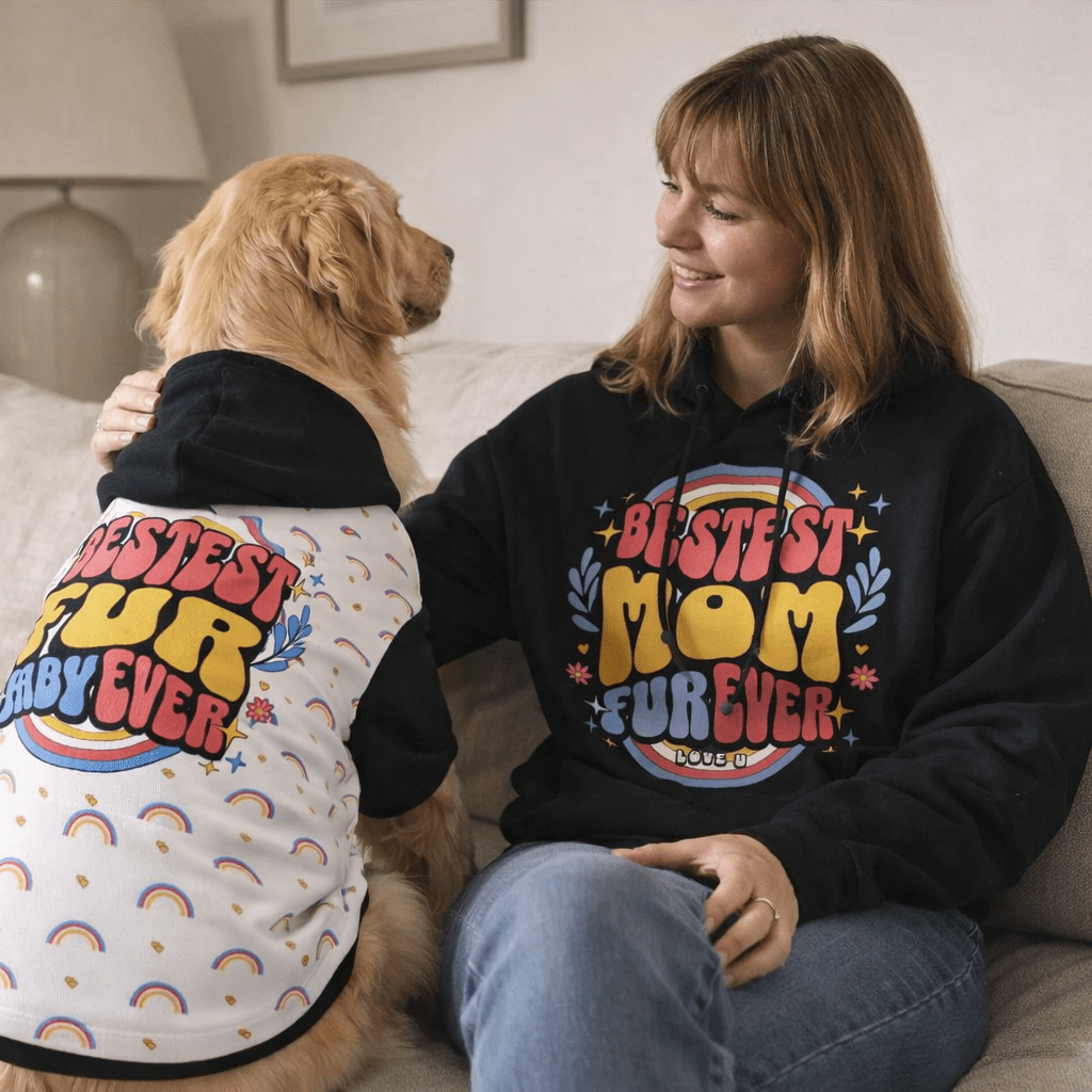 Woman and dog sitting on a couch wearing matching 'Bestest Fur Mom Ever' sweatshirts.