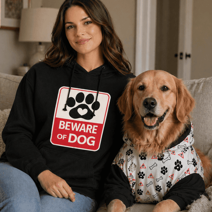 Woman wearing a hoodie with a 'Beware of Dog' sign sitting on a couch with a dog.