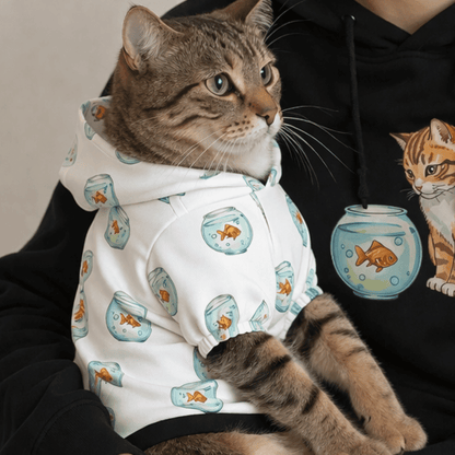 Cat wearing a hoodie with fishbowl design held by a person in a black hoodie with a cat graphic.