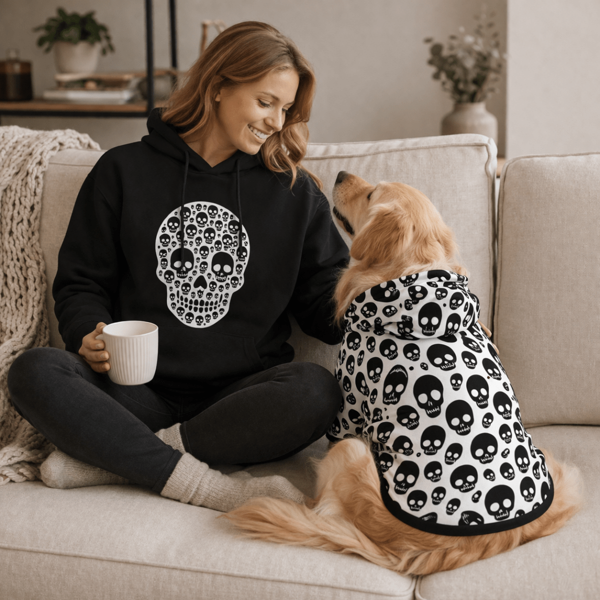Woman sitting on a couch with a dog wearing a skull-patterned outfit, both wearing matching outfits.