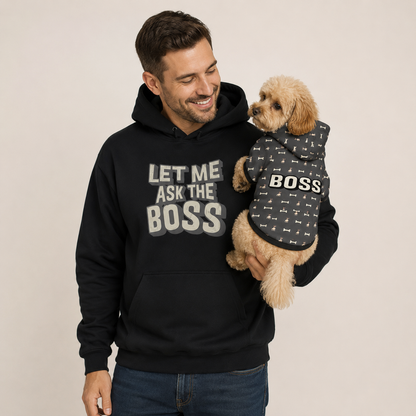 Man wearing a black hoodie with 'Let Me Ask The Boss' text, holding a dog in a matching 'BOSS' hoodie.