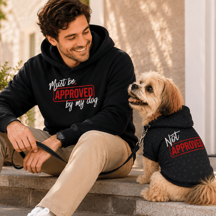 Man in 'Must Be Approved By My Dog' hoodie sitting with his dog wearing the matching 'Not Approved' hoodie